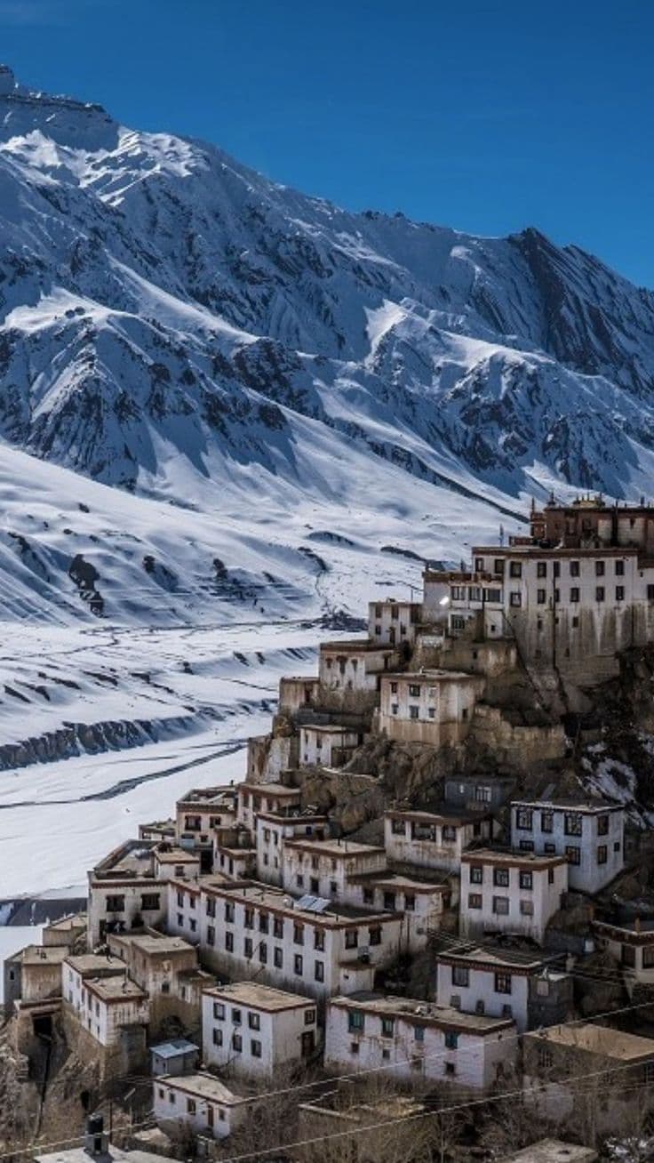 Hairpin road winding through the cold desert of Spiti Valley with snow-capped peaks